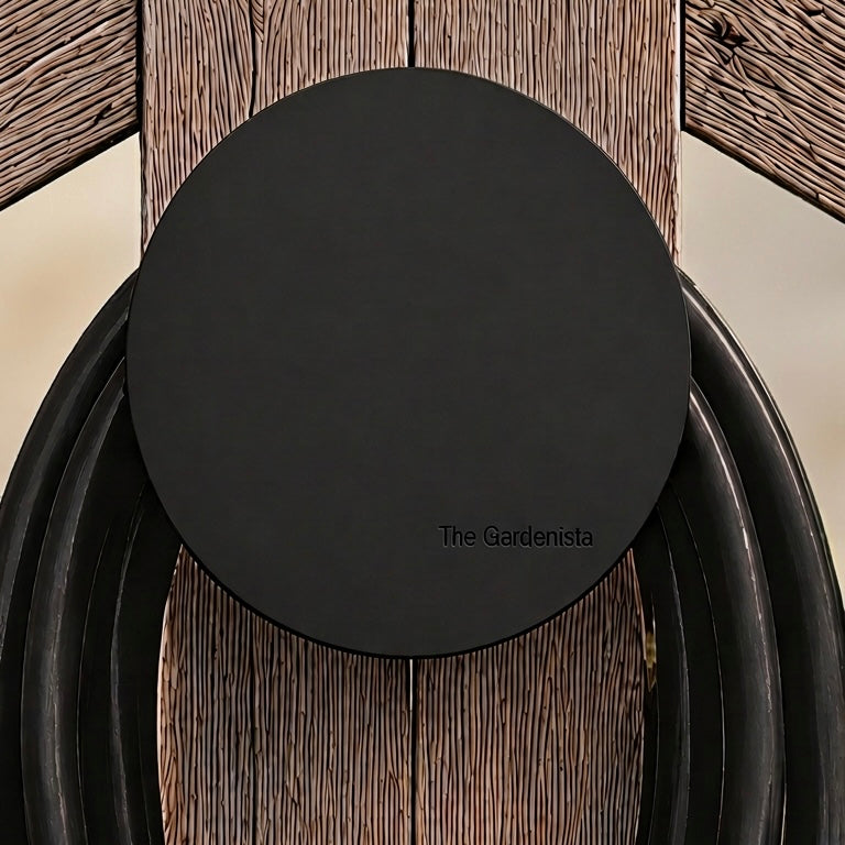 Front view of The Gardenista large black hose holder with black garden hose on a timber gate.