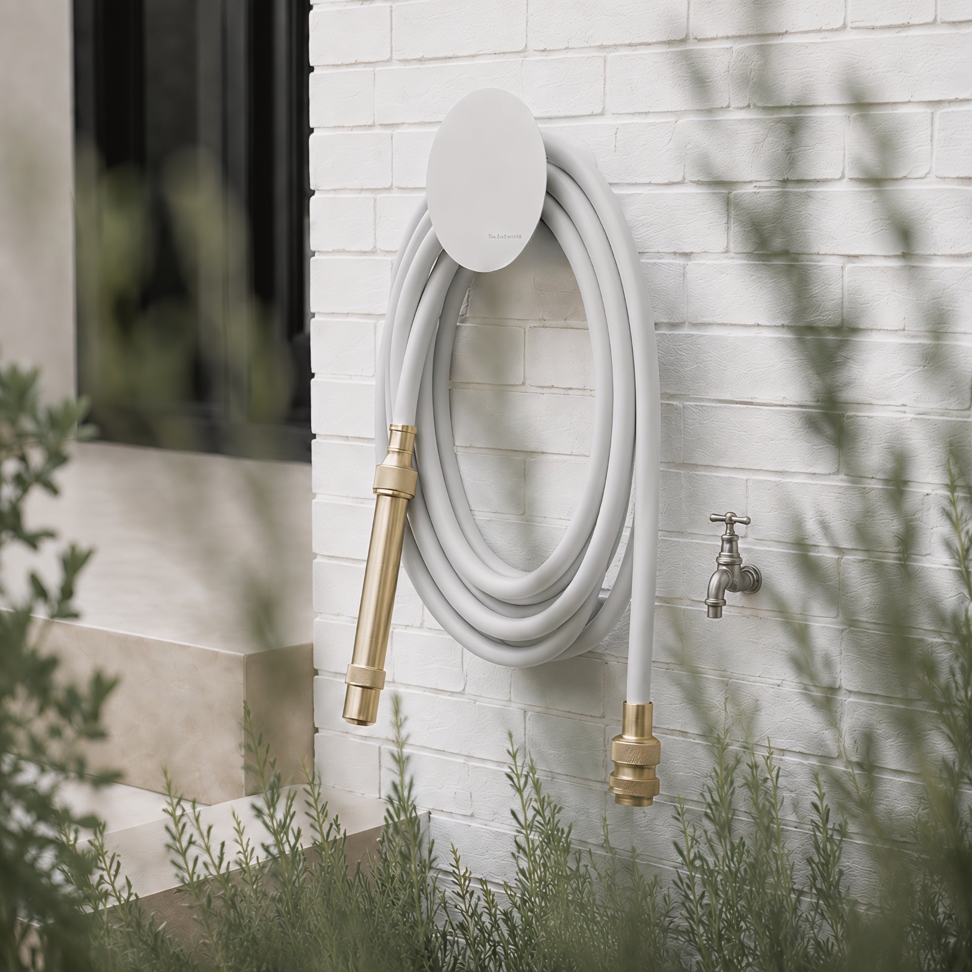 Soft grey hybrid garden hose and white wall-mounted hose holder in a contemporary garden setting.