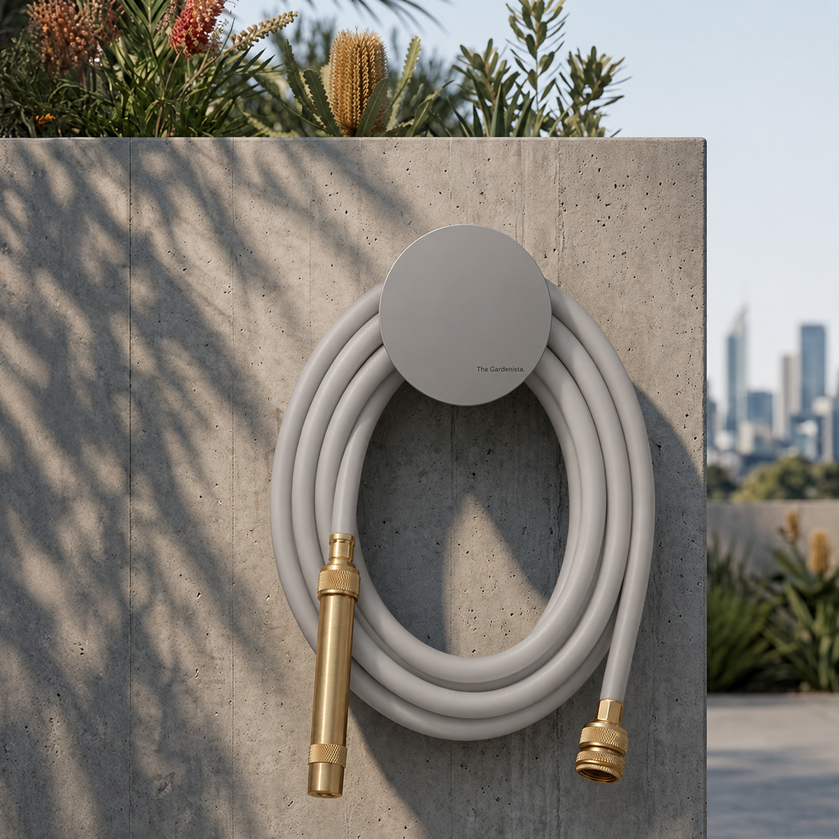 Soft grey hybrid garden hose on a grey wall-mounted hose holder in a modern urban garden setting.