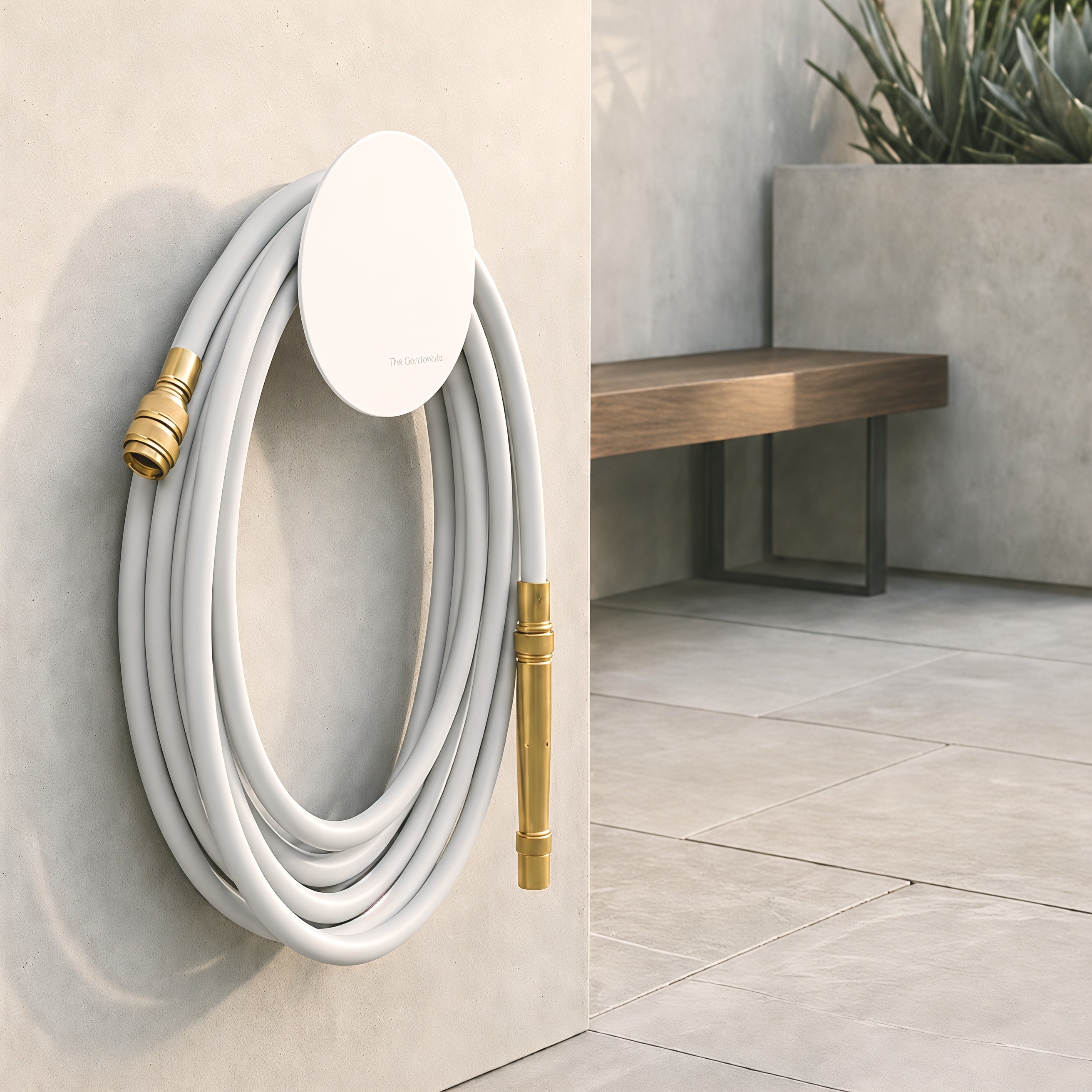 Soft grey hybrid garden hose loosely draped over a white wall-mounted hose holder in a modern outdoor setting.