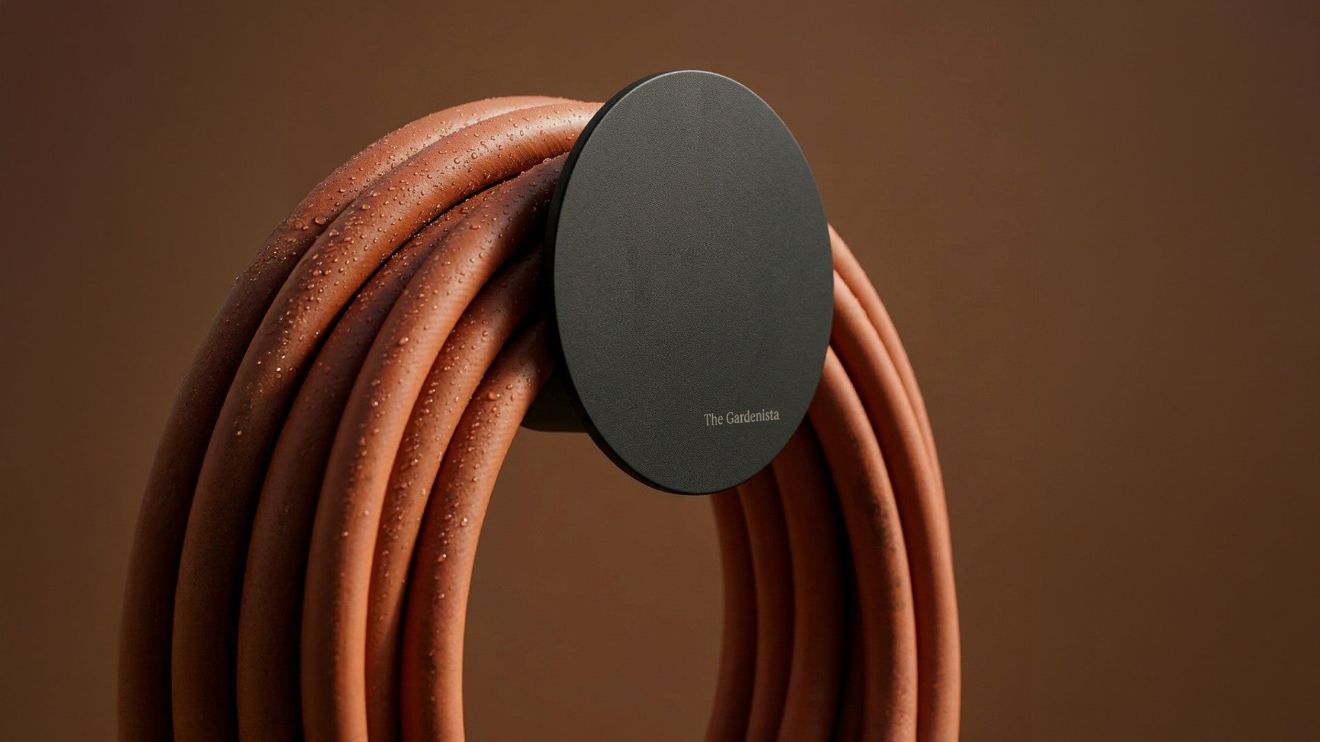 Rust Hybrid Garden Hose with matte black Spot Hose Holder and brass tap in a Mediterranean garden setting