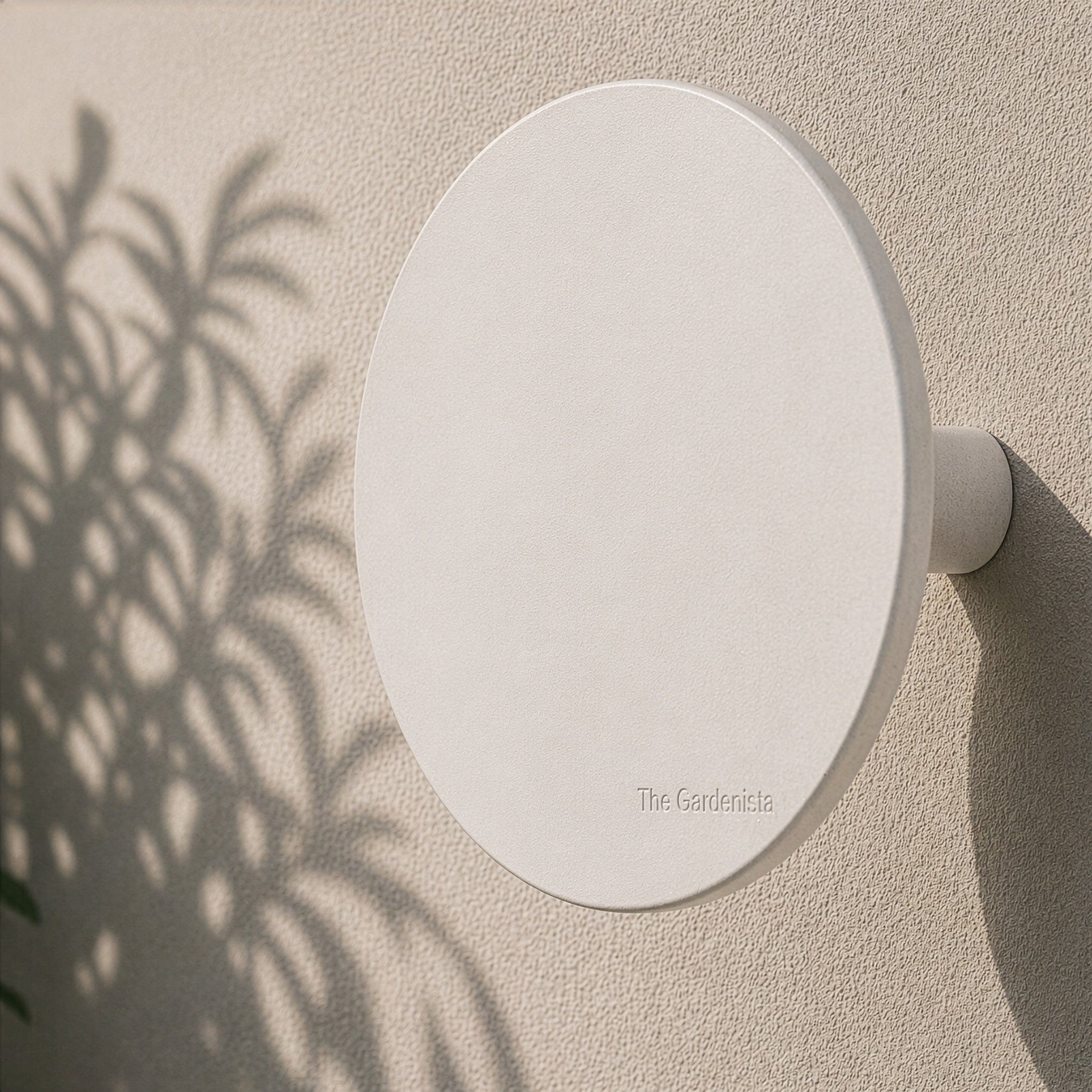 Side view of the large white wall-mounted hose holder showing its circular face and projection from the wall.