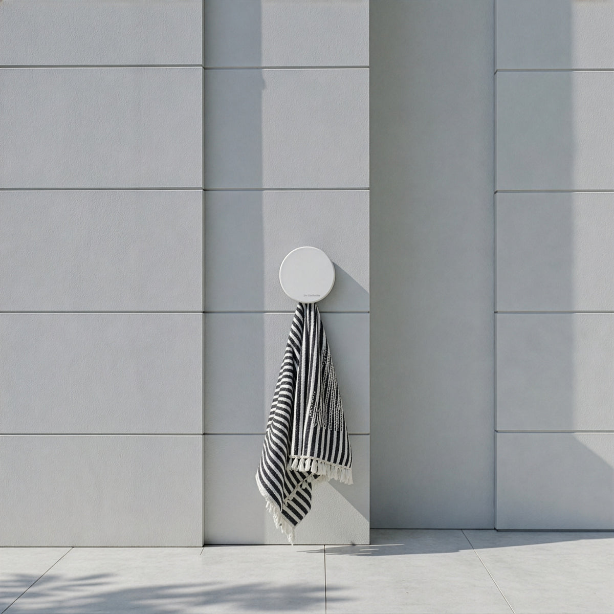 Small white wall-mounted holder displaying a black and white striped outdoor towel.